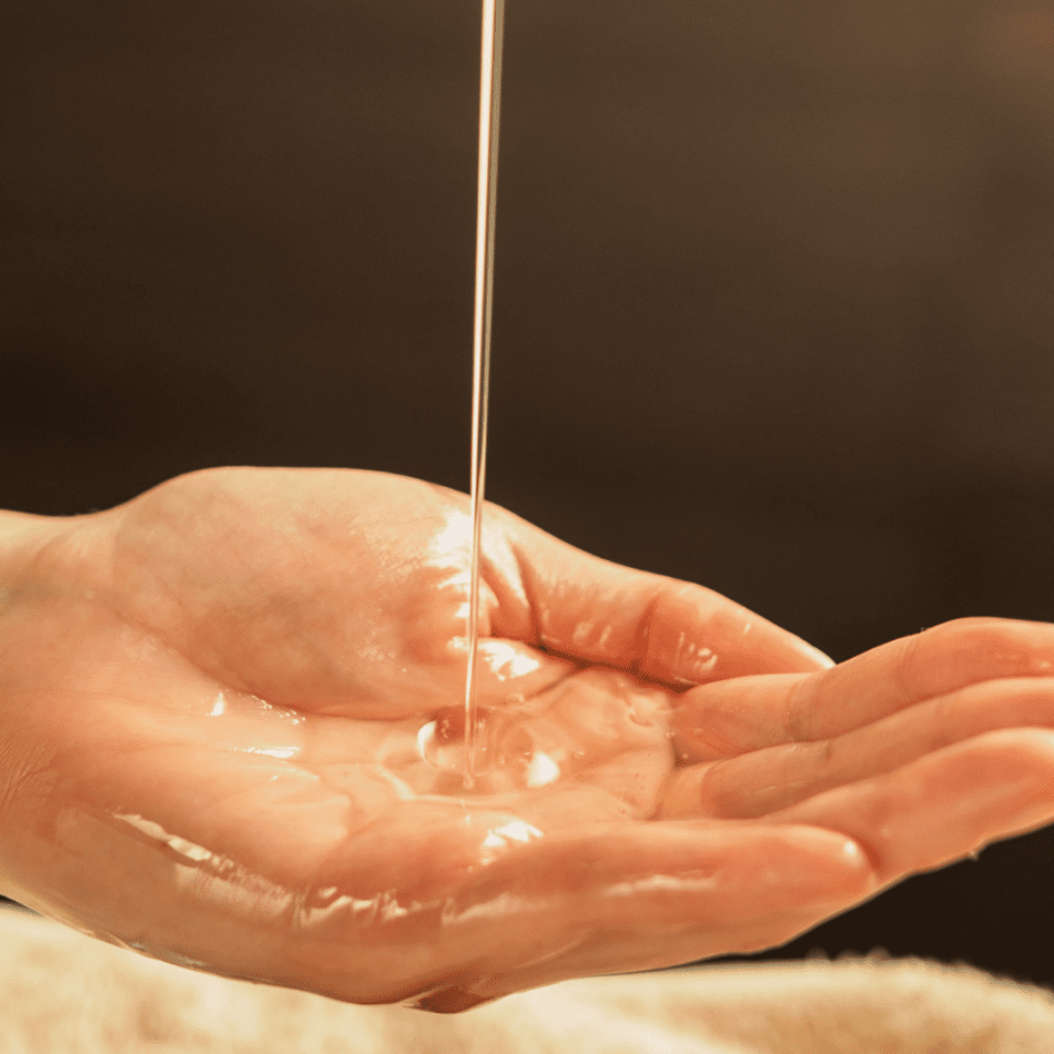 Massage oil being poured into massage therapists hands before starting the massage.