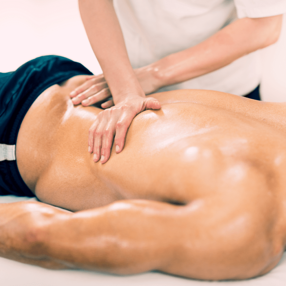 Male having a sports massage. Massage therapists hands working on his low back.